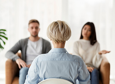 Marital Therapy. Professional Psychologist Sitting Back To Camera During Appointment With Unhappy Couple In Office. Rear View, Selective Focus